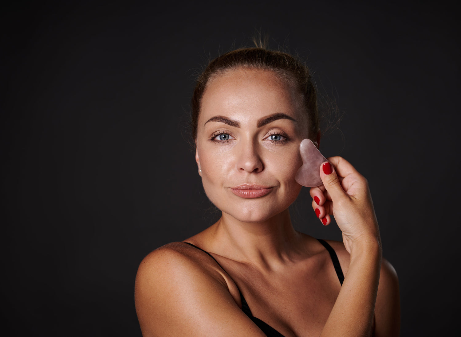 Woman using a jade gua sha stone for facial massage