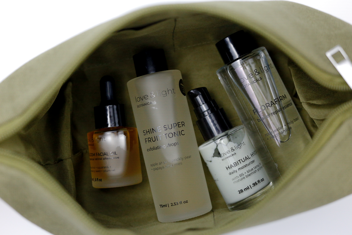 Inside a sage hemp-jute cosmetic case holding Bloom facial oil, Shine superfruit tonic, Habitual hydrator + Florafirm barrier repair essence